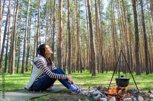 Young woman in the woods near the fire with a pot photo