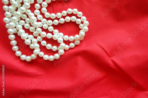 Close up of pearl necklace on red background. 