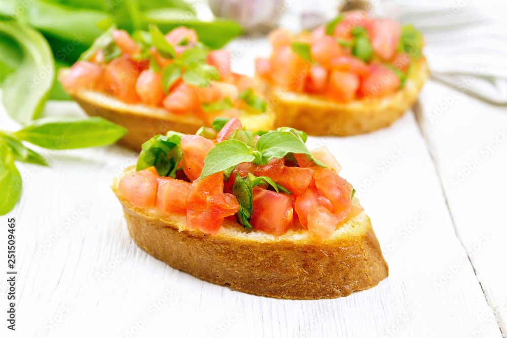 Bruschetta with tomato and spinach on light wooden board Bruschetta with tomato and spinach on light wooden board