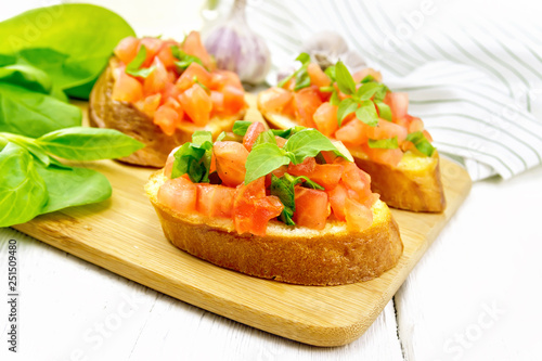 Bruschetta with tomato and spinach on white table