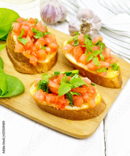 Bruschetta with tomato and spinach on white wooden board