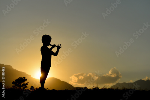silhouette of boy playing the flute