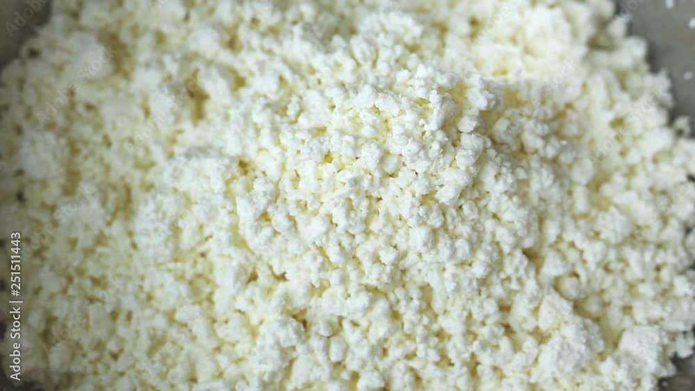 low-fat, useful from cow's milk, white crumbly curd is poured from above into an iron bowl. cooking cottage cheese low-fat, useful from cow's milk, white crumbly curd is poured from above into an iron bowl. cooking cottage cheese