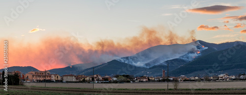Overview of Mount Pisano in flames at sunset from Bientina, Tuscany, Italy