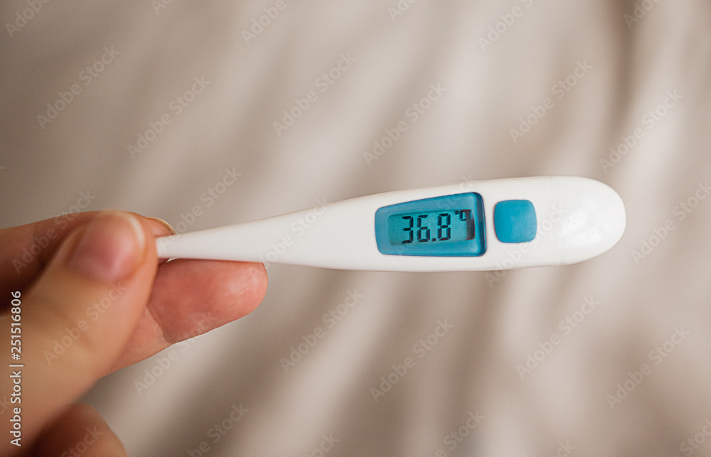 Obraz premium Female hand holds digital thermometer with temperature
