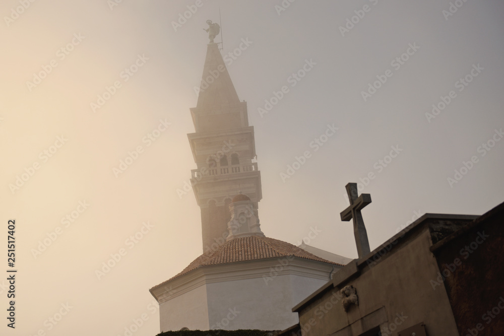 Cross and church in mist. Piran, Slovenia