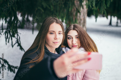 Two young friends are photographed against the backdrop of the winter forest