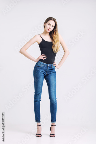 Model beautiful young girl with blond hair and blue eyes in a t-shirt and jeans fashionable in the Studio