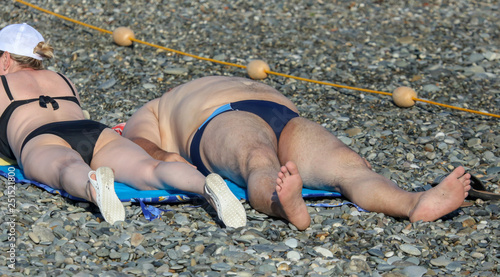 People sunbathe on the beach to the sea