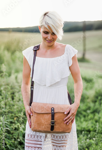 Foto A front view of woman standing in nature with a brown leather bag