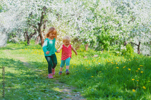 happy girls play run in spring nature, kids enjoy apple blossom