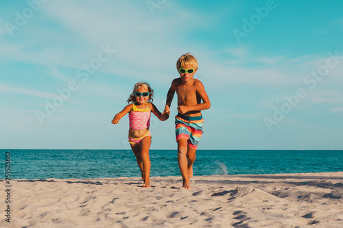 happy little boy and girl running at beach