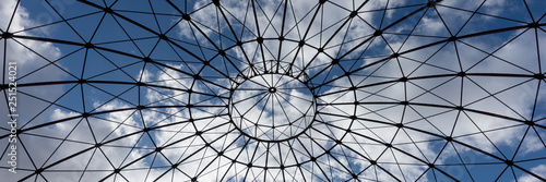 Bottom view of an iron structure with blue sky and clouds in the background photo