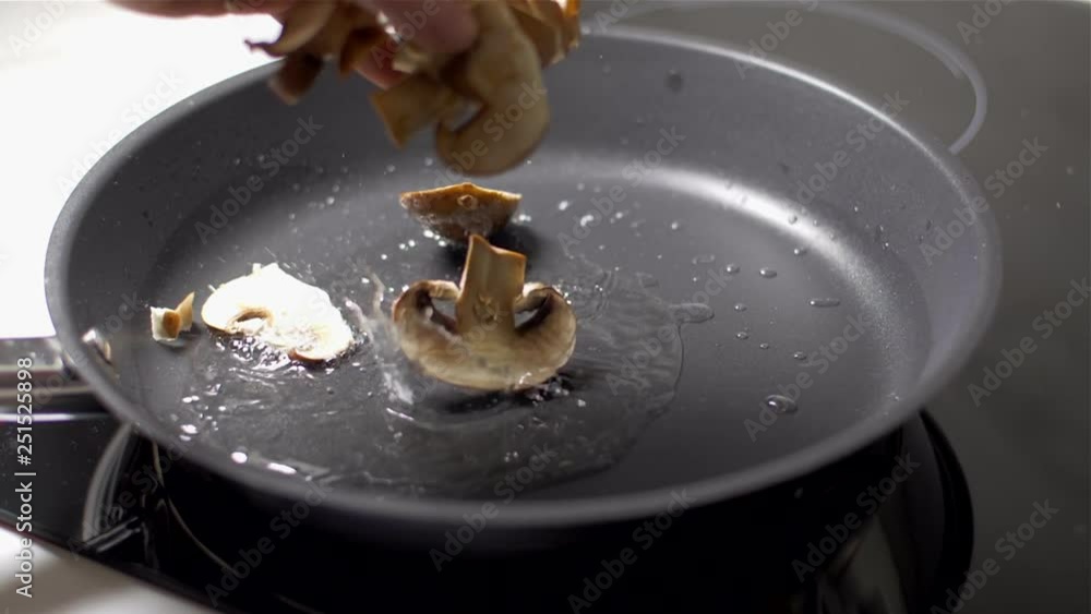 Closeup of hands putting a mushrooms at hot frying pan Slow motion Closeup of hands putting a mushrooms at hot frying pan Slow motion