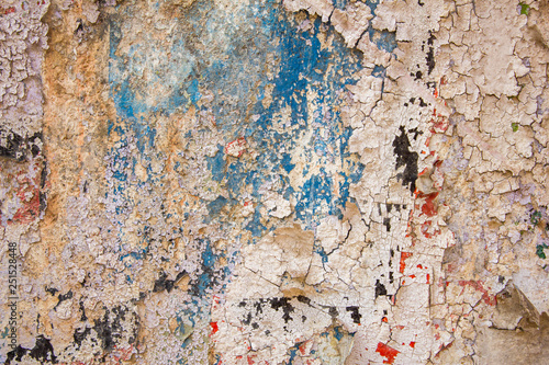 old blue wall with damage, cracks and white peeling paint with red and black spots. rough surface texture