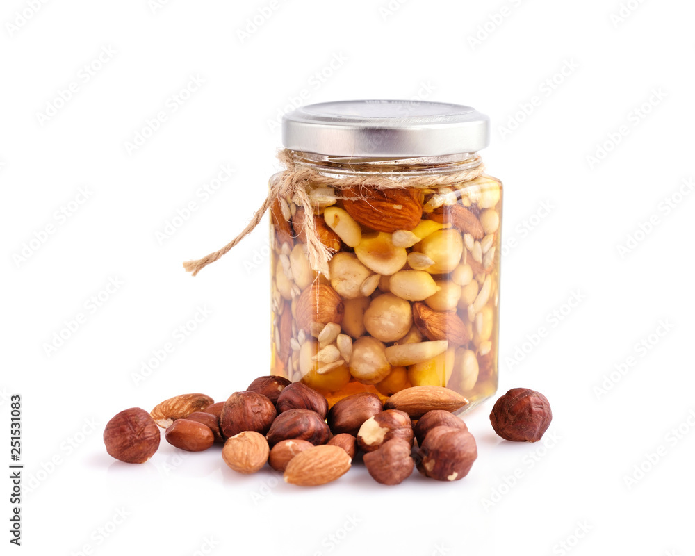 Healthy mix of natural honey with different nuts in a jar on white background