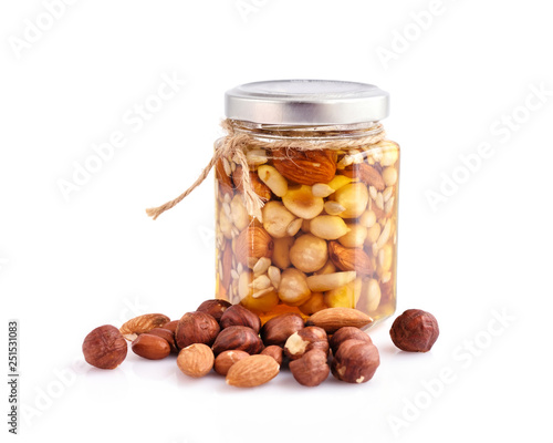 Healthy mix of natural honey with different nuts in a jar on white background