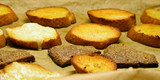 Fried baguette and rye bread slices on baking tray.