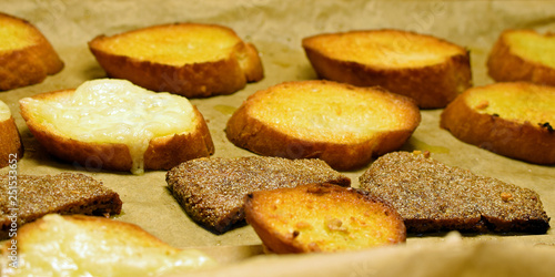 Fried baguette and rye bread slices on baking tray.