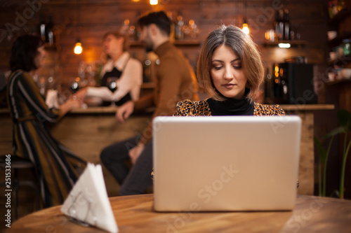 Blonde businesswoman working on her laptop in a coffee shop