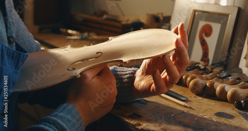 Close up of professional master artisan luthier painstaking detailed work on wood violin in a workshop. photo
