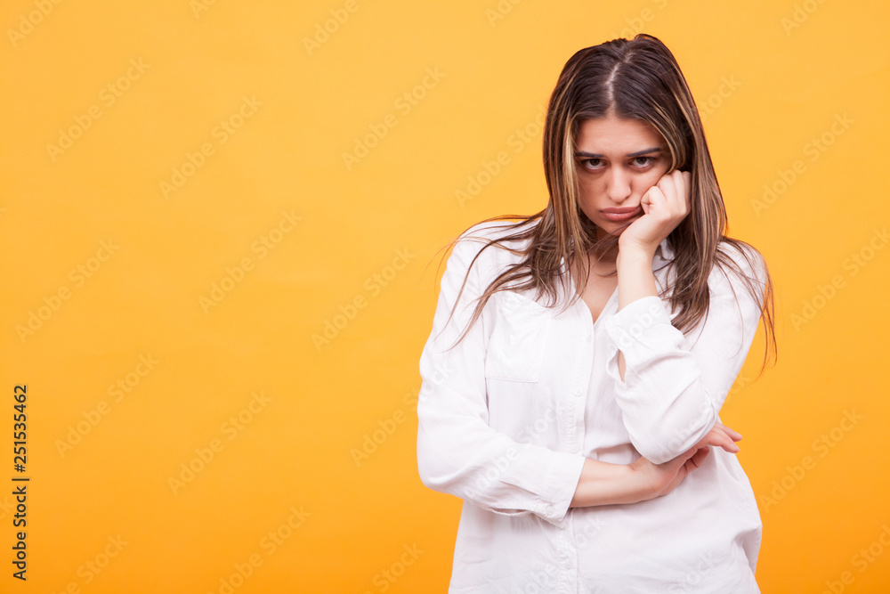 Upset young girl wearing white shirt over yellow background Upset young girl wearing white shirt over yellow background