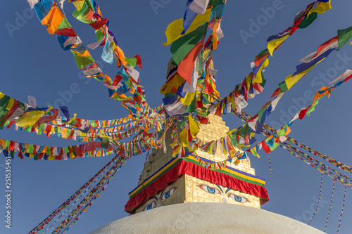 Boudhanath Tibetan Buddhist Stupa with colorful prayer flags against a clear blue sky