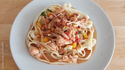 Homemade chicken pasta served on wooden table.