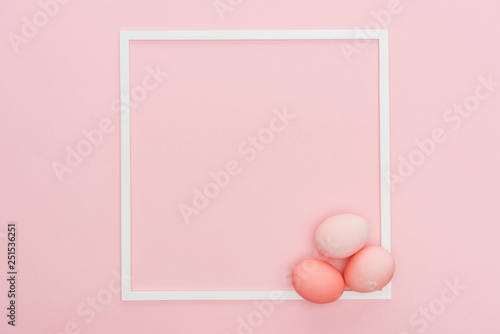 top view of pastel easter eggs with empty frame isolated on pink