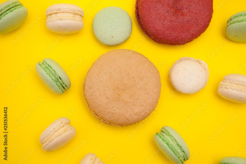 Fototapeta premium Top view of delicious french macaroons over yellow background