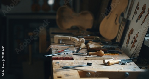 Fotografie Close up of raw violin with different violin maker work tools on workbench in a workshop of professional master artisan luthier