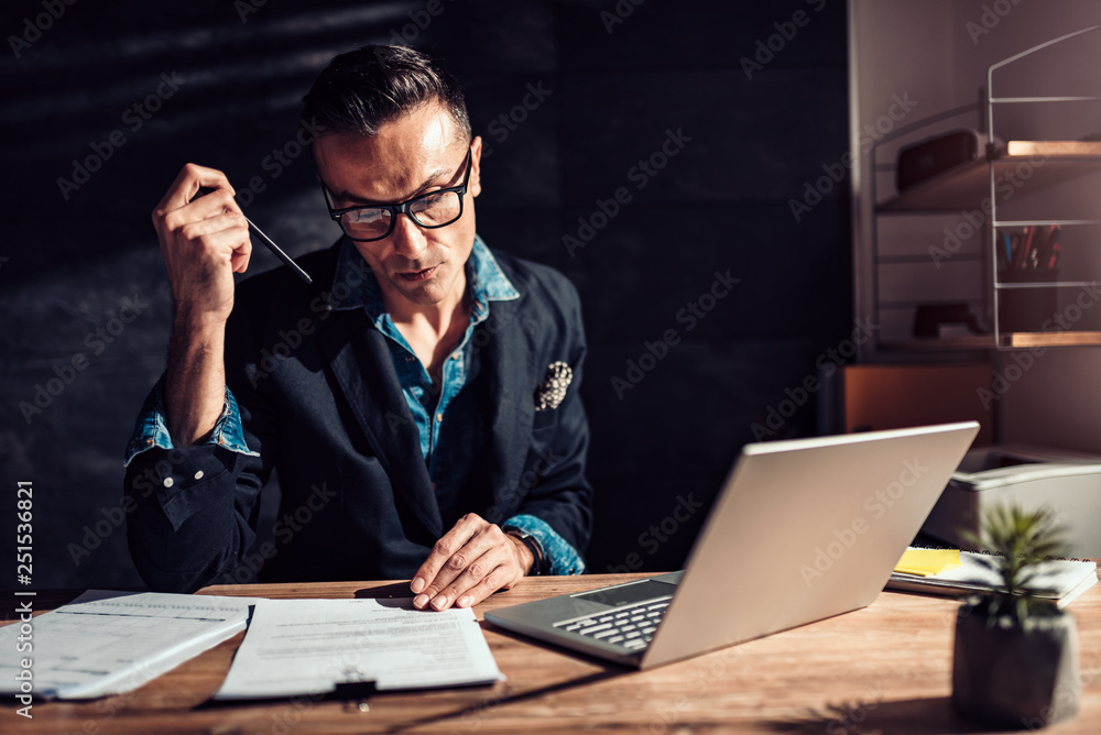 Businessman reading contract in his office Businessman reading contract in his office