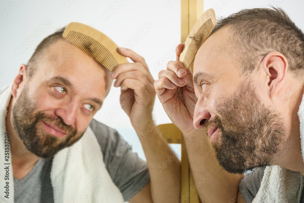 Obraz premium Man using comb in bathroom