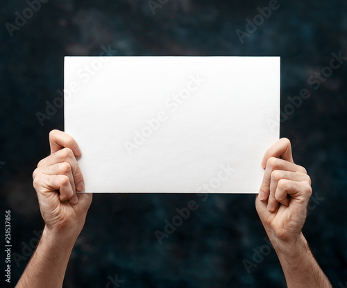 Hands holding blank white paper isolated over black