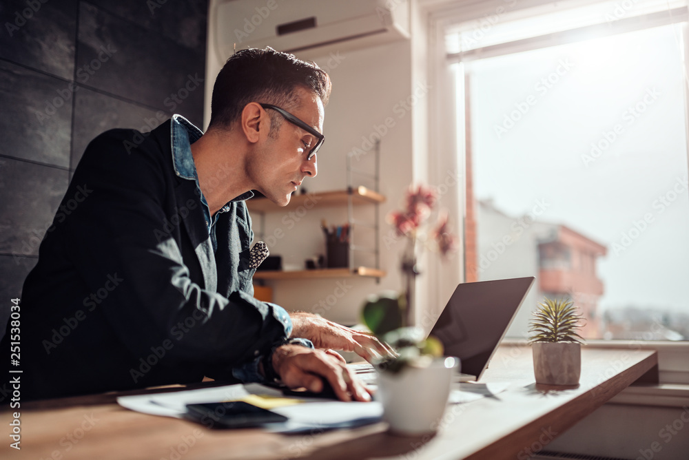 Businessman sitting at his desk and using laptop in the office Businessman sitting at his desk and using laptop in the office