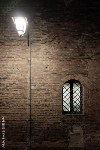 a scary streetlight and window in a brick wall, Montagnana, Padova - Dicembre 2018
