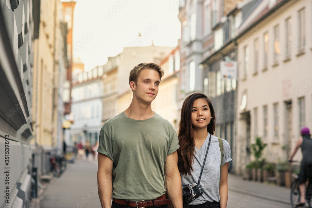 Smiling young couple holding hands while walking in the city