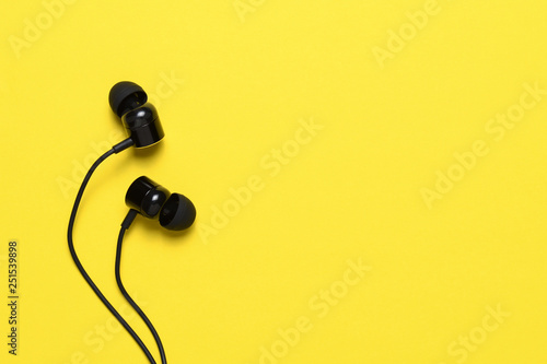Earbuds on yellow background with text space photo