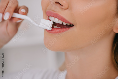 cropped view of smiling woman brushing teeth