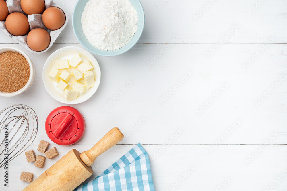 White wooden table background with baking ingredients. Butter, flour, eggs, sugar and cooking utensils. Ingredients for baking cookies, cake, dough preparation with copy space for text, recipe, menu White wooden table background with baking ingredients. Butter, flour, eggs, sugar and cooking utensils. Ingredients for baking cookies, cake, dough preparation with copy space for text, recipe, menu