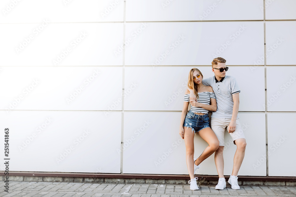 Hipster young loving couple in fashionable sun glasses walking together, embrace each other, hugging and having fun in summer. Urban, love, happiness concept Hipster young loving couple in fashionable sun glasses walking together, embrace each other, hugging and having fun in summer. Urban, love, happiness concept
