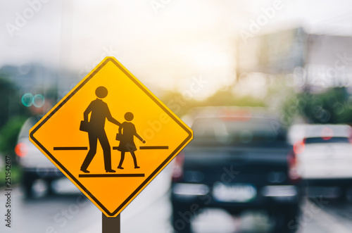Fototapeta School zone warning sign on blur traffic road with colorful bokeh light abstract background