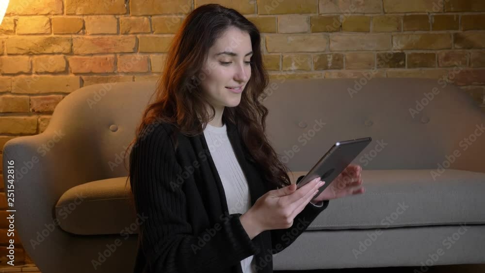 Young caucasian girl with wavy hair sitting on floor showing green screen of tablet in cosy home atmosphere. Young caucasian girl with wavy hair sitting on floor showing green screen of tablet in cosy home atmosphere.