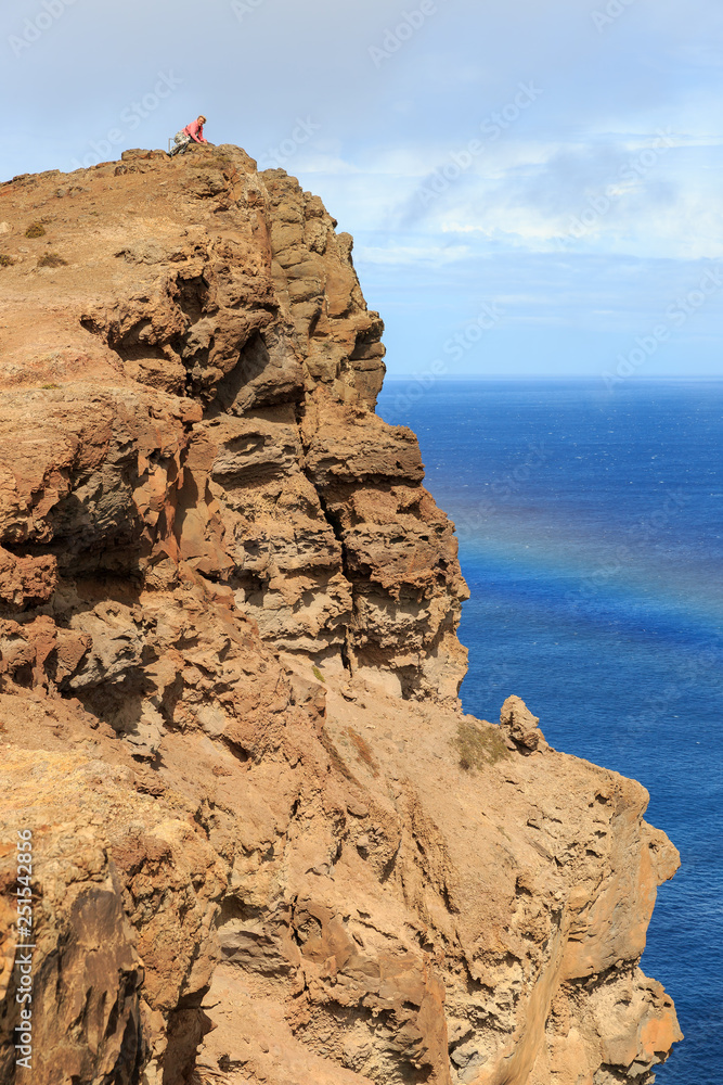 Tourist on the cliffs in the beautiful landscape with rainbow of the east coast of the island Madeira at Ponta de Sao Lourenco nature reserve