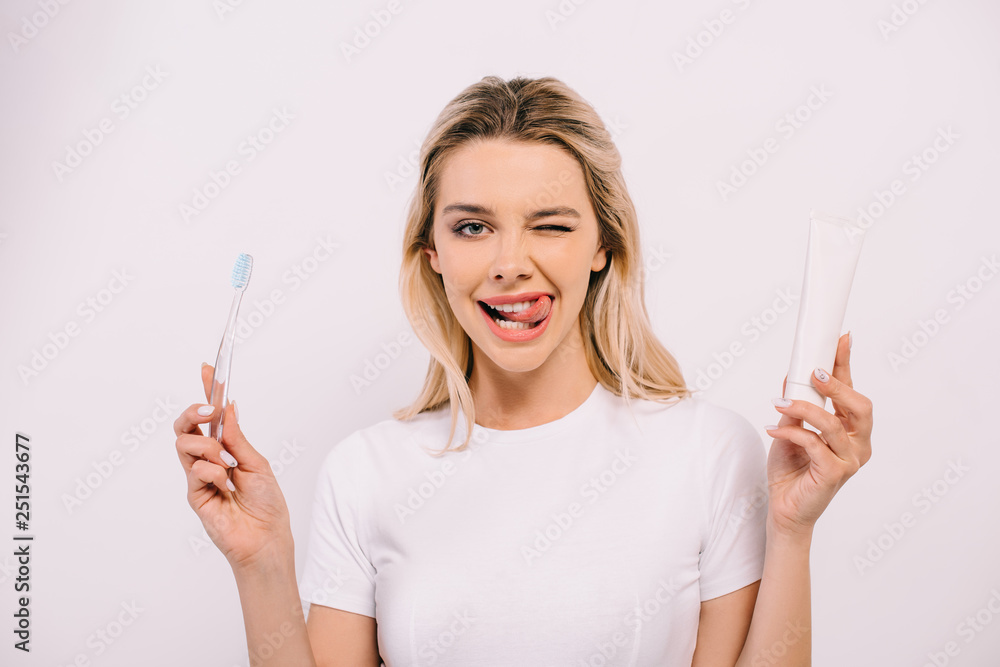 beautiful woman sticking tongue out while holding toothbrush and toothpaste with copy space isolated on white beautiful woman sticking tongue out while holding toothbrush and toothpaste with copy space isolated on white