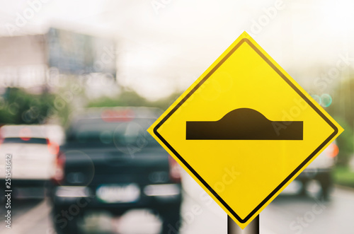 Canvas Print Hump warning sign on blur traffic road with colorful bokeh light abstract background