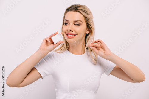 beautiful smiling woman holding dental floss and looking away isolated on white