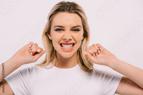 beautiful woman biting dental floss and looking at camera isolated on white