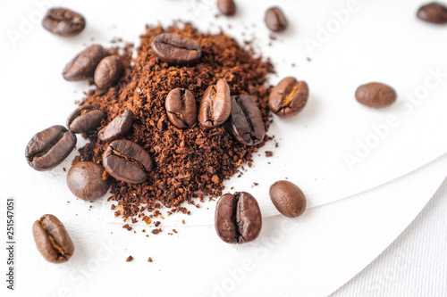 Close up dark roasted coffee beans and coffee ground on white cotton fabric and white filter paper  background in natural light 