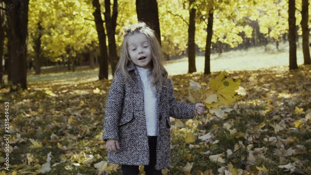 Beautiful little girl shows bouquet of leaves at camera and throws up them Beautiful little girl shows bouquet of leaves at camera and throws up them